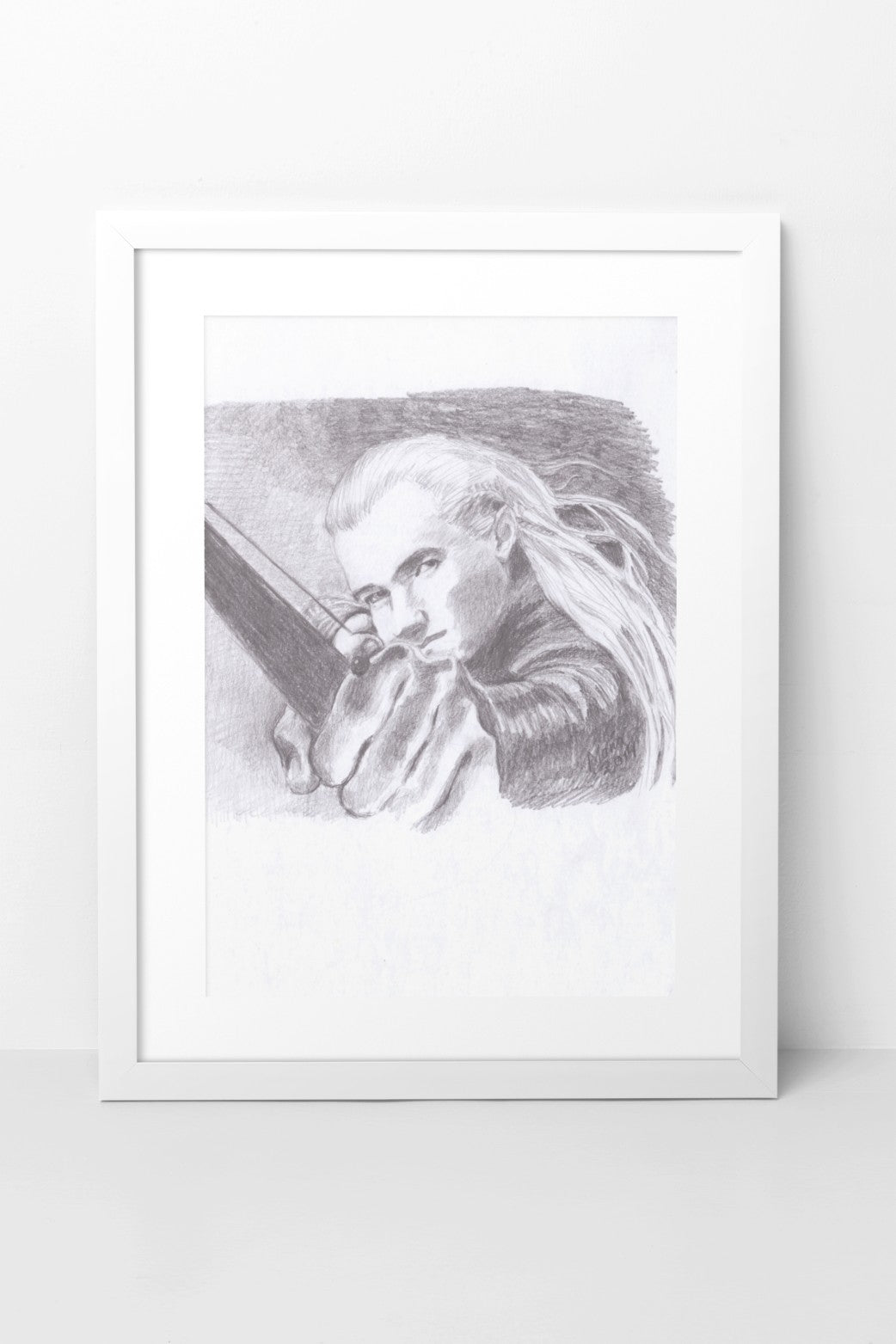 Pencil drawing in grayscale featuring Orlando Bloom as Legolas from The Lord of the Rings. The artwork shows a close-up of Legolas from the front, with his hand outstretched as he draws a bow and arrow. His hair flows gently in the wind, adding a sense of movement to the piece. The artwork is displayed in a white mock-up frame against a neutral background, emphasizing the detailed shading and dynamic composition.