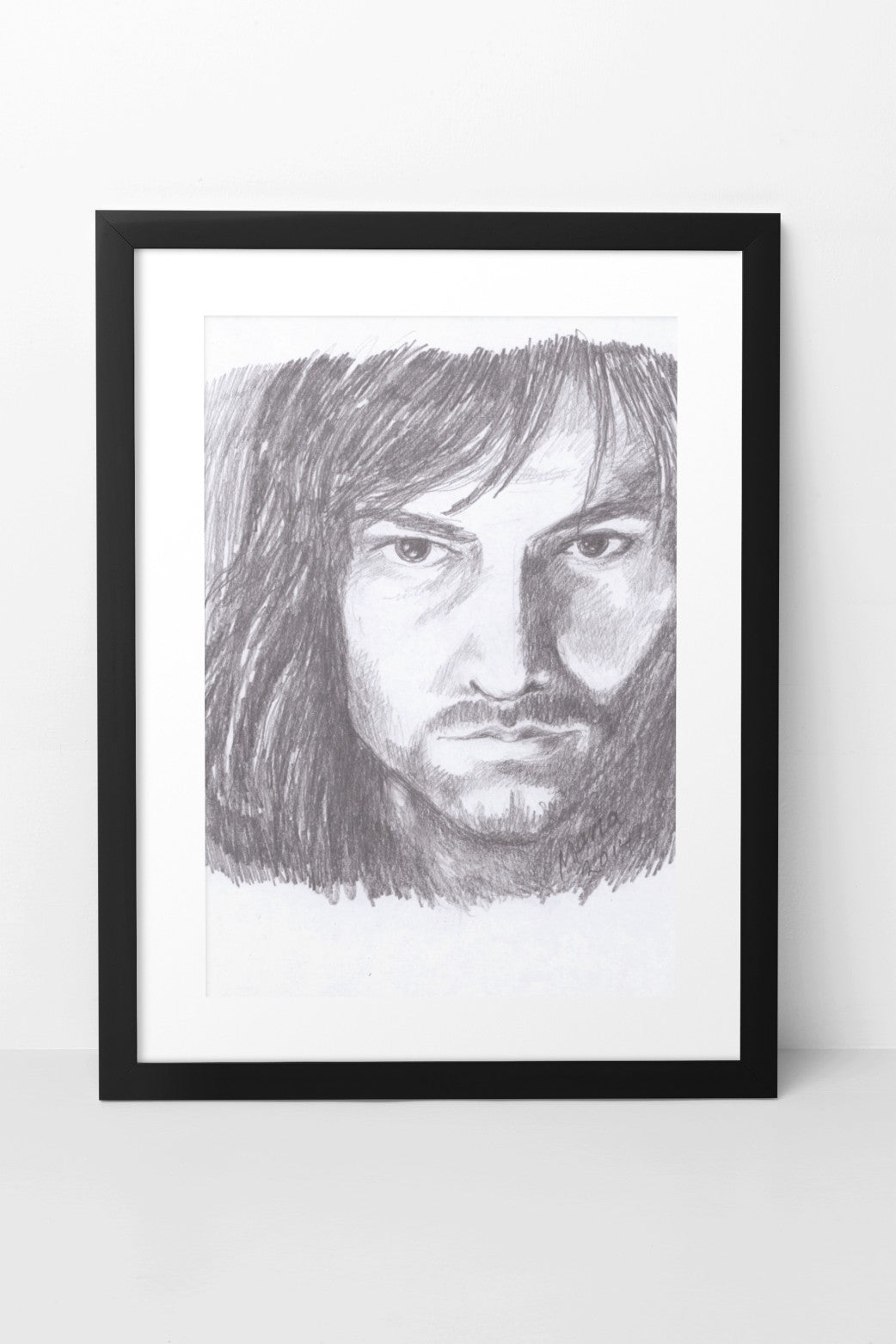 Pencil drawing of Aidan Turner as Kili from The Hobbit, featuring a close-up of his face with a serious expression as he looks straight forward. The A5-sized artwork is displayed in a black mock-up frame against a neutral background, emphasizing the character's intense gaze and detailed facial features.