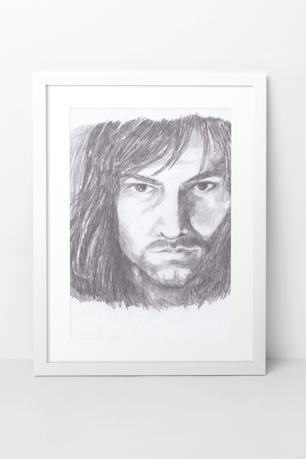 Pencil drawing of Aidan Turner as Kili from The Hobbit, featuring a close-up of his face with a serious expression as he looks straight forward. The A5-sized artwork is displayed in a white mock-up frame against a neutral background, emphasizing the character's intense gaze and detailed facial features.