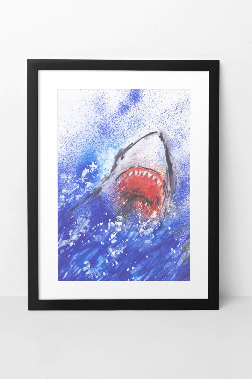 Pen drawing on glossy paper of a shark leaping out of deep blue waters with white splashes. The shark is shown from the front, with its gaping mouth and sharp teeth prominently visible. The A4-sized artwork is displayed in a black mock-up frame against a neutral background, highlighting the dynamic energy and sharp detail of the piece.