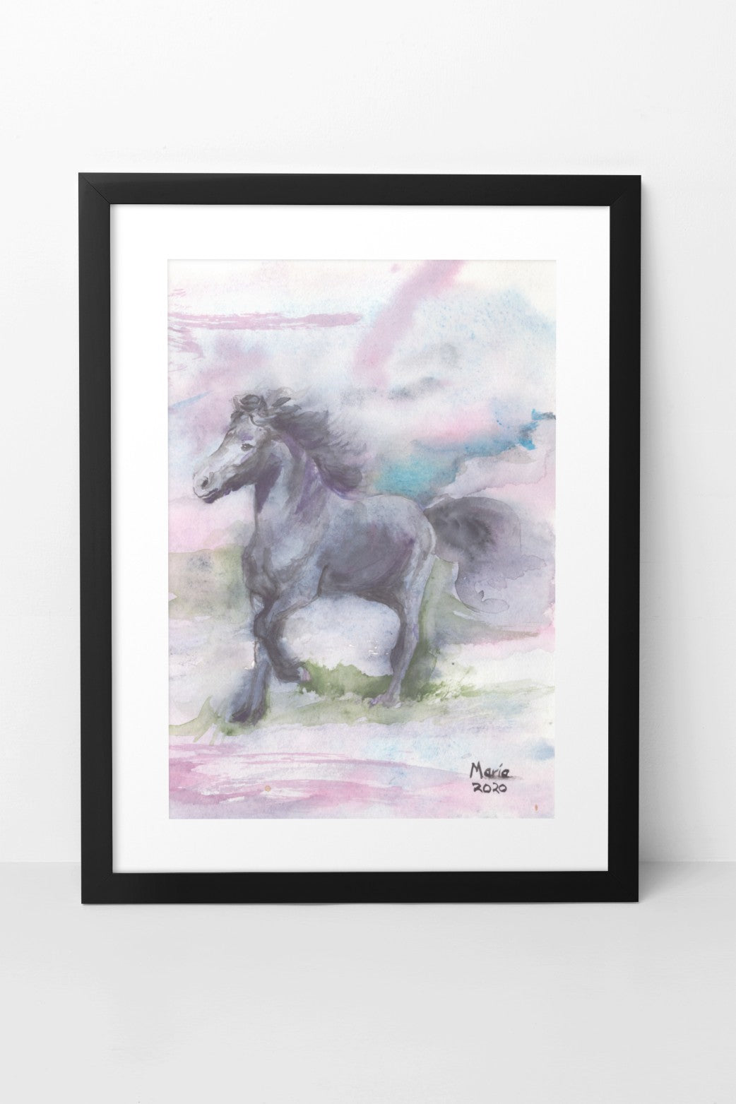 Watercolor painting of an Icelandic horse named Manni, trotting and frolicking on green grass, moving to the left. Manni is black with a matching black mane. The background features soft shades of pink, blue, and green, creating a gentle and serene scene. The A4-sized artwork is displayed in a black mock-up frame against a neutral background, highlighting its soft colors and playful mood.
