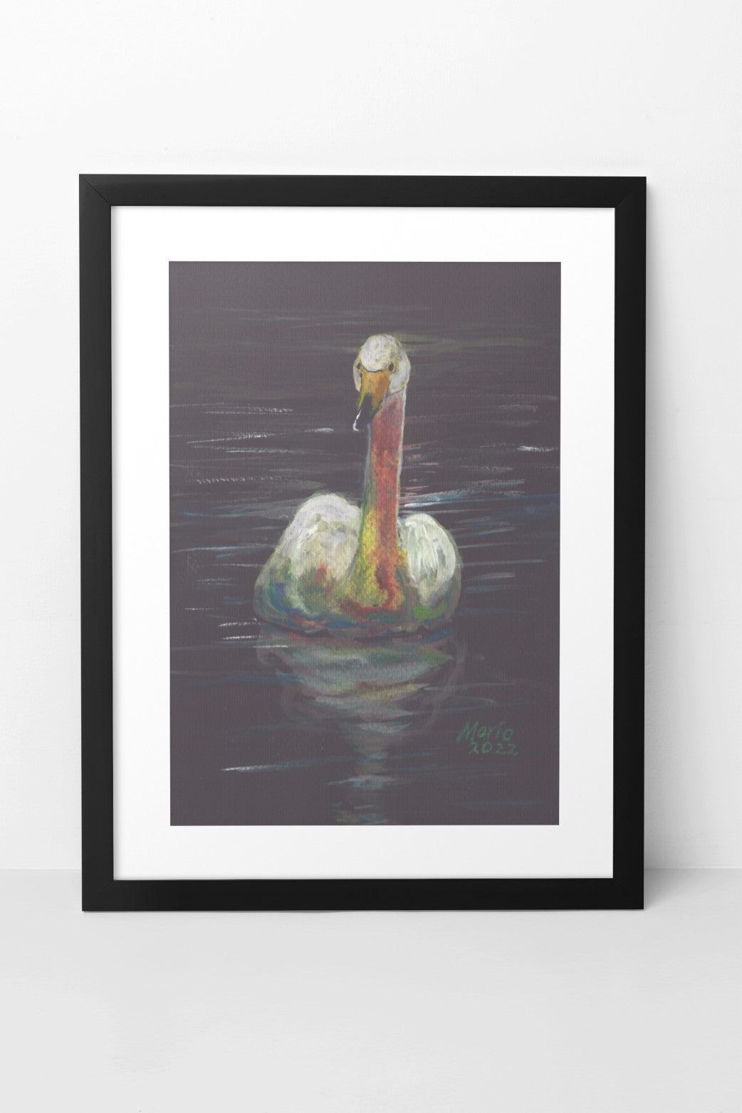 Gouache painting on black watercolor paper of a delicate white swan with an orange-tinted neck and a yellow and black beak. The swan is swimming in still water, with its reflection clearly visible. The A4-sized artwork is displayed in a black mock-up frame against a neutral background, highlighting the swan's delicate details and serene reflection.