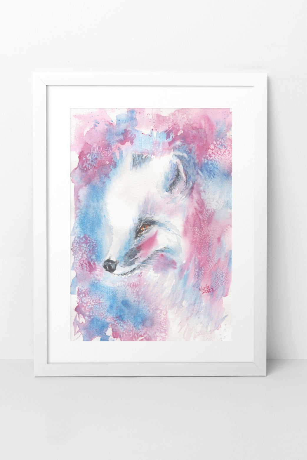 Watercolor painting of an Arctic fox, showing a close-up of its face as it looks to the left. The fox has fluffy white fur, brown eyes, a black nose, and a red brush stroke on its cheeks. The background features red, blue, and white hues. The slightly smaller-than-A3 artwork is displayed in a white mock-up frame against a neutral background, emphasizing the fox’s delicate features and vibrant colors.