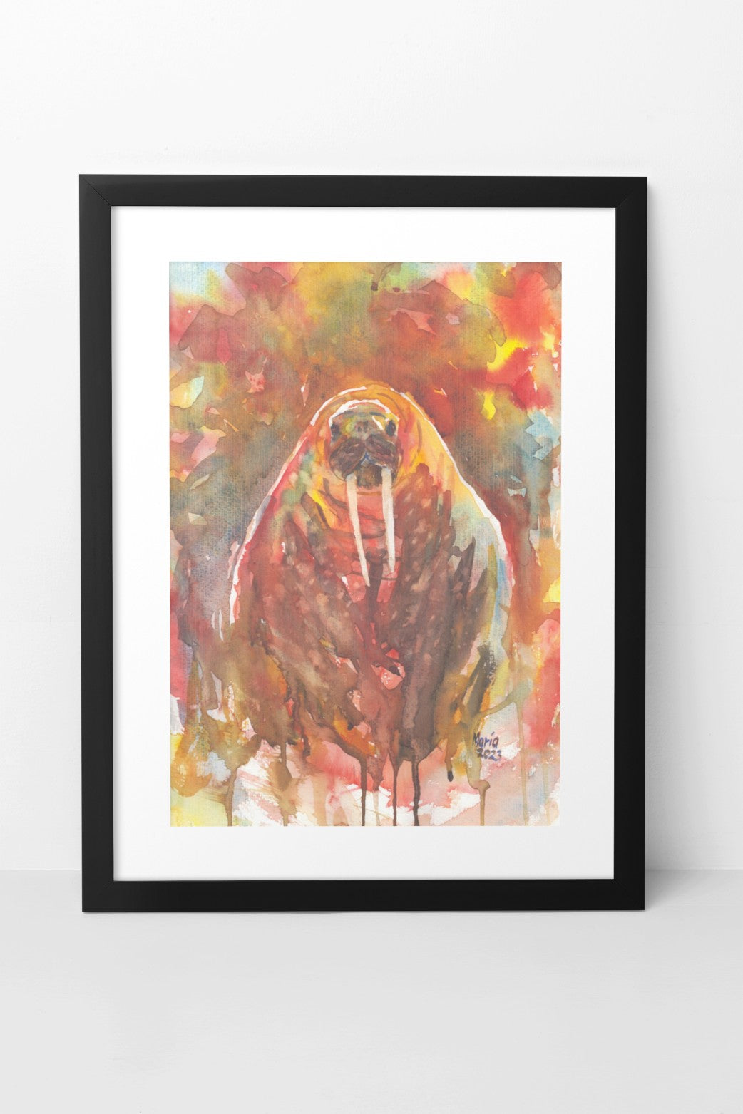Watercolor painting of a walrus in earthy tones, depicted from the front. Both the walrus and the background feature hues of brown, red, yellow, green, blue, and white. The scene gives the impression of the walrus either peeking up from the water or walking on land. The A3-sized artwork is displayed in a black mock-up frame against a neutral background, highlighting the vibrant earthy tones and composition.